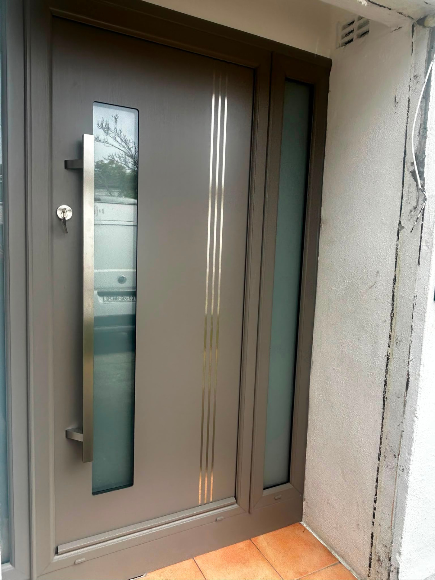 Modern grey composite front door with brushed steel inlays and frosted sidelight