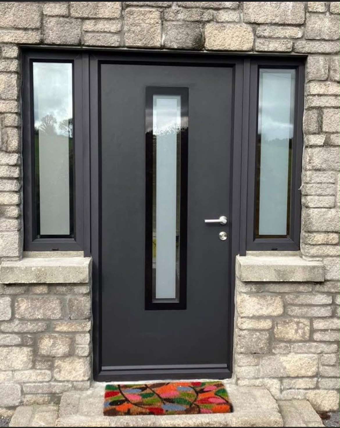 Black contemporary front door with slim frosted glass panel and twin sidelights