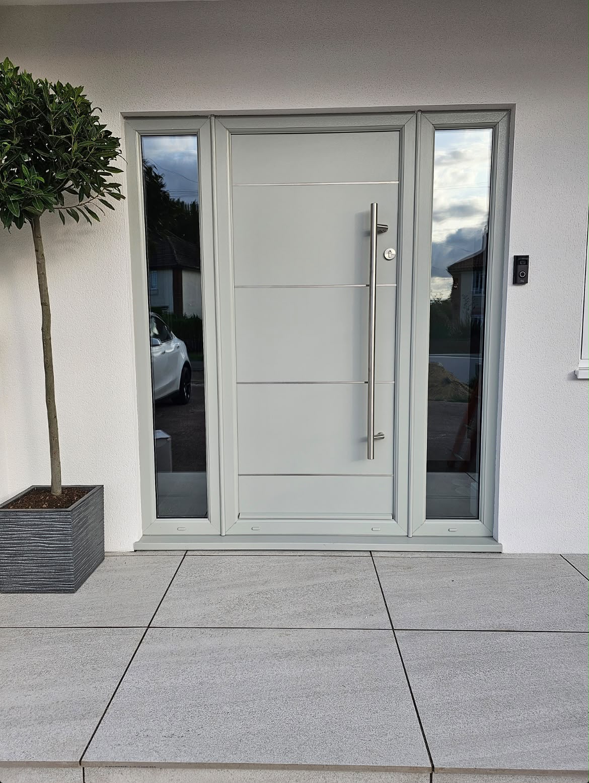 Agate grey contemporary front door with steel inlays, bar handle and twin sidelights