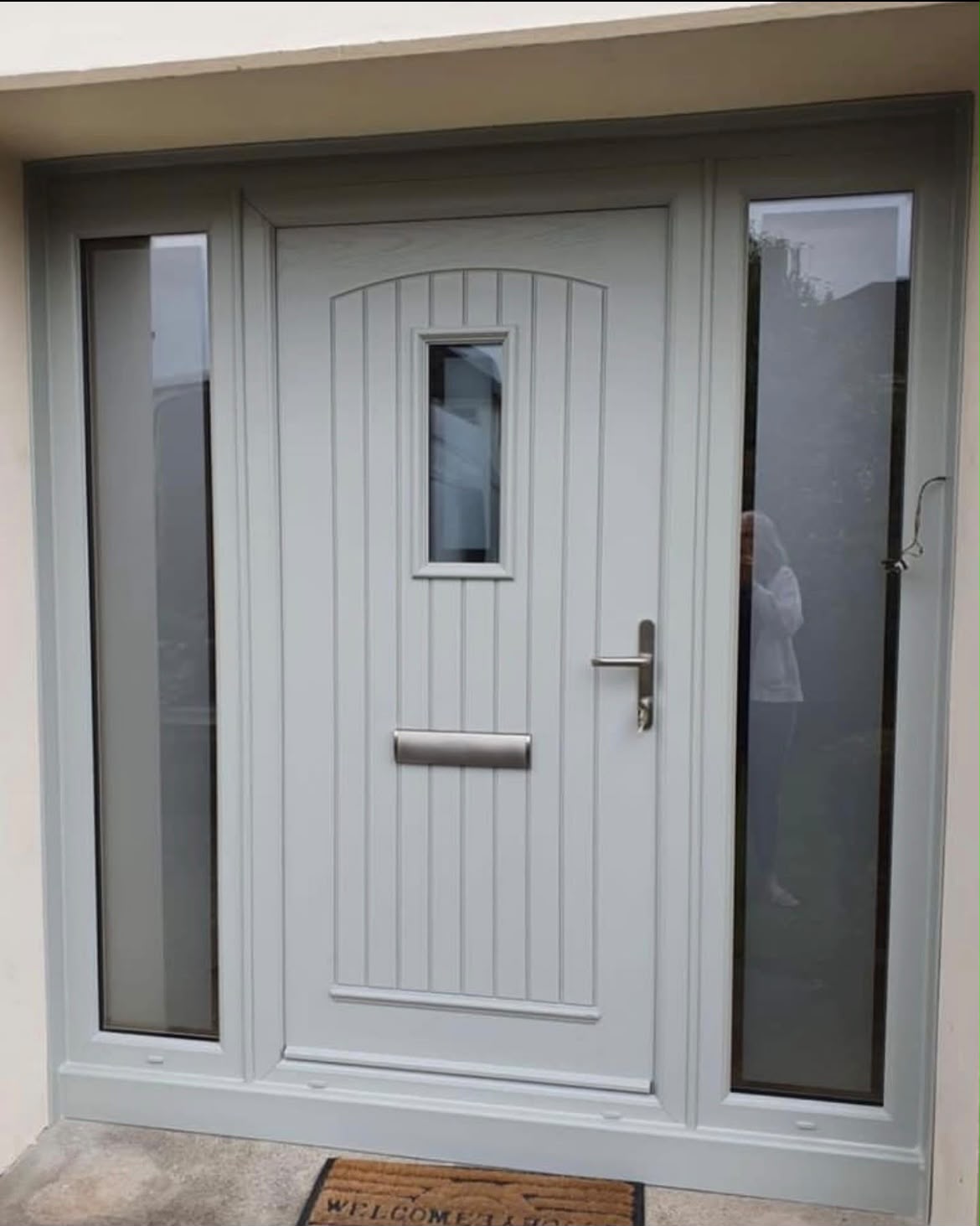 Painted grey cottage style composite front door with small glass panel and twin sidelights
