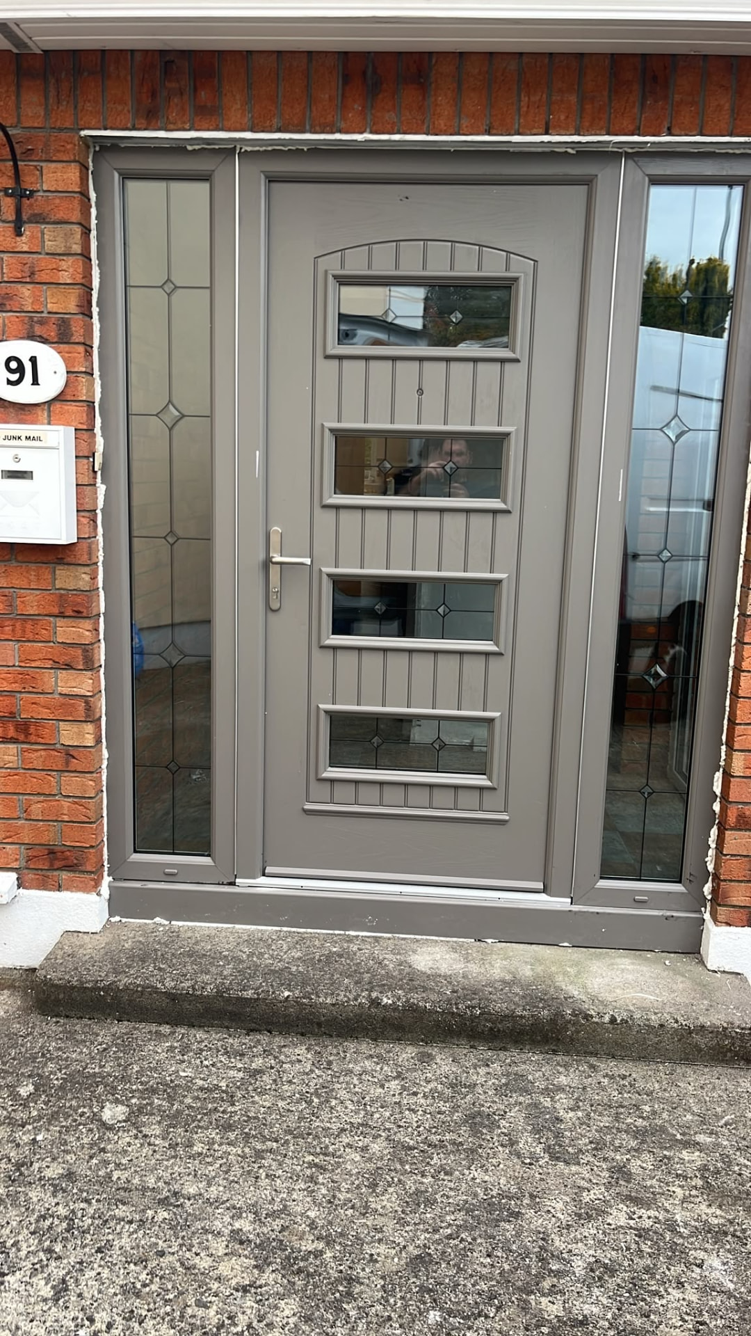 Grey composite front door with four glass panels and decorative sidelights