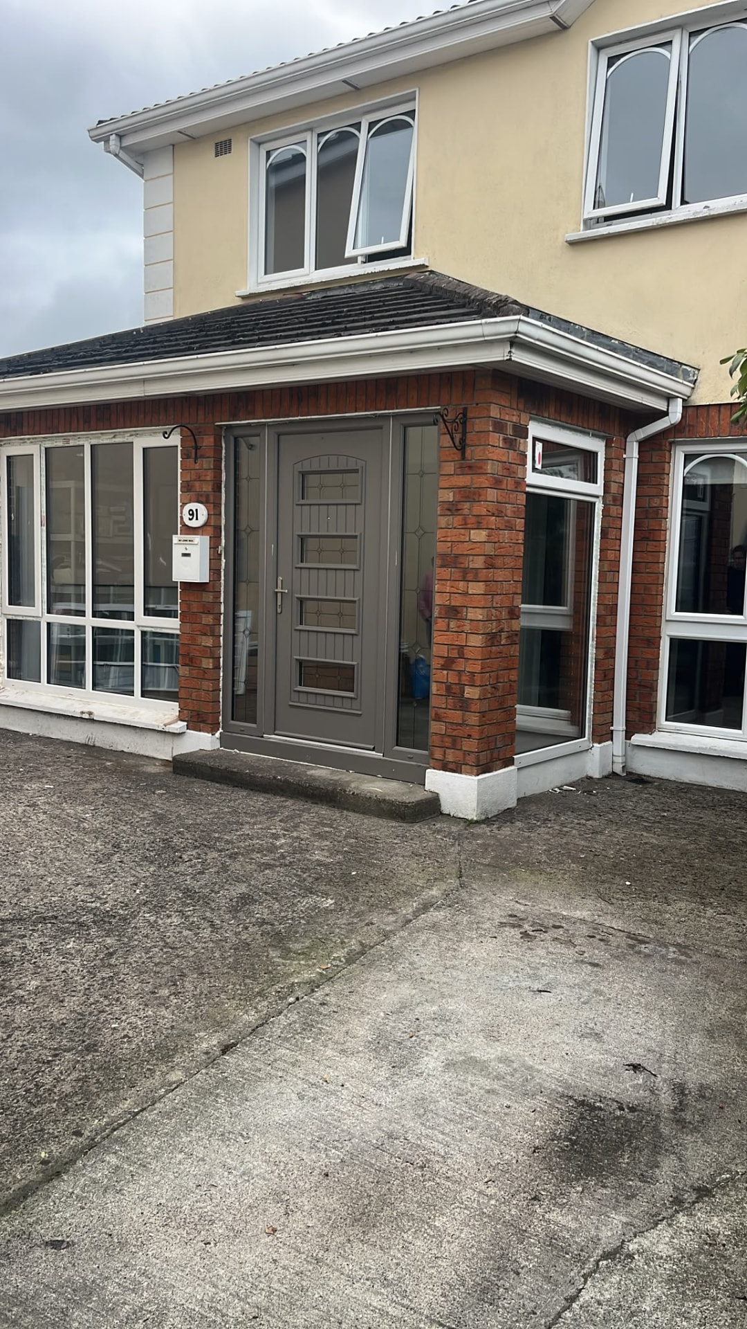 Grey composite front door with sidelights on a brick porch extension