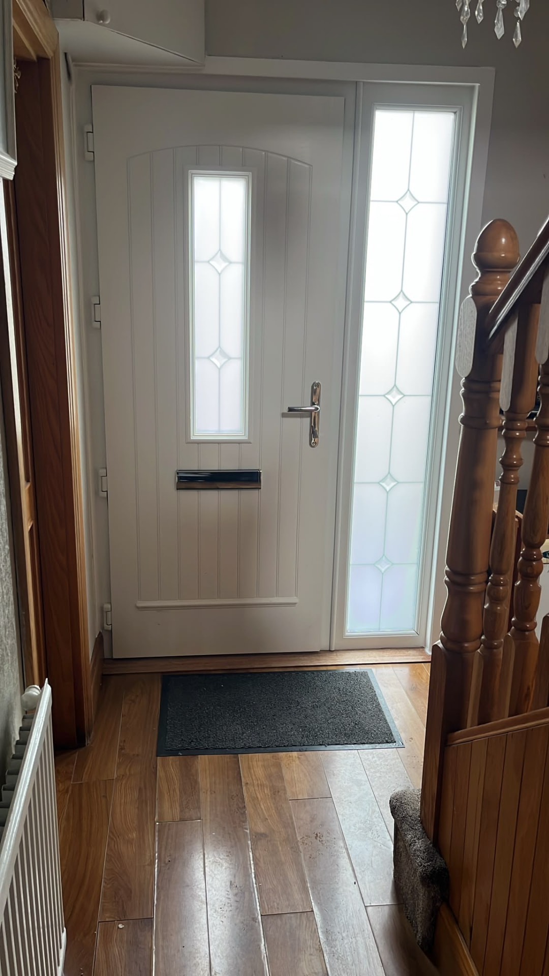 White composite front door with frosted glass panel and sidelight viewed from the hallway