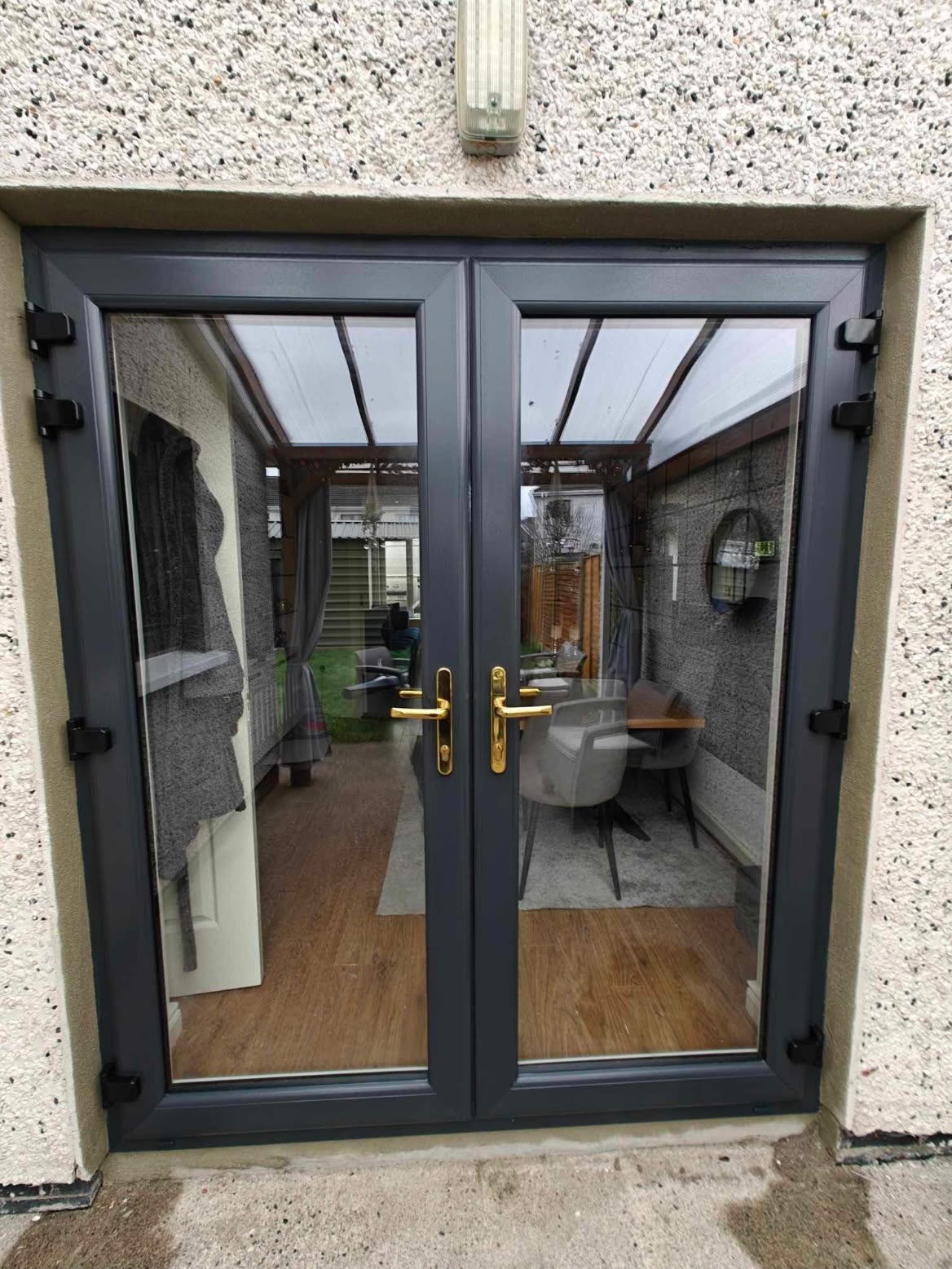 Anthracite grey PVC French doors with gold handles to a garden room