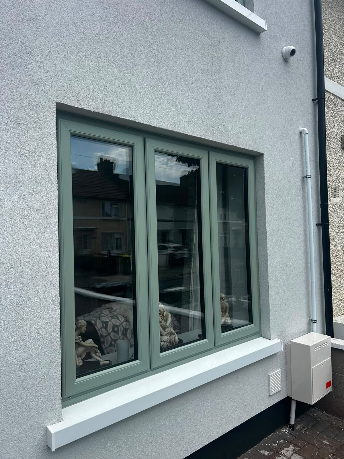 Sage green triple casement window with white sill fitted to a rendered Dublin house